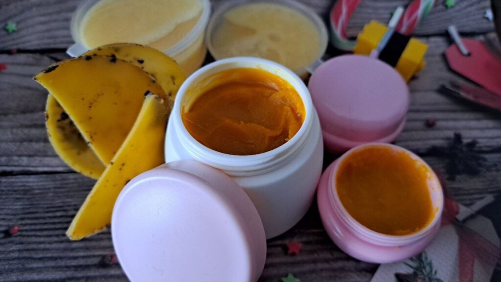 Баночки в яких Зволожуючий бальзам для губ з обліпихою зроблений вдома з доступних інгредієнтів, віск, мед, бджола на різдв'яному фоні