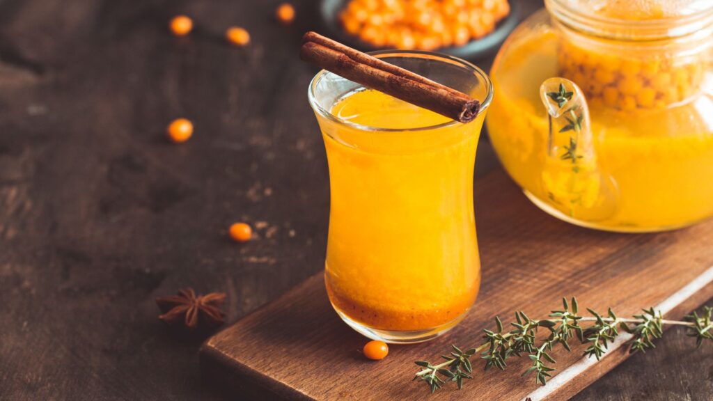 Теплий чай з обліпихи та свіжі ягоди обліпихи, кориця, чебрець на столі